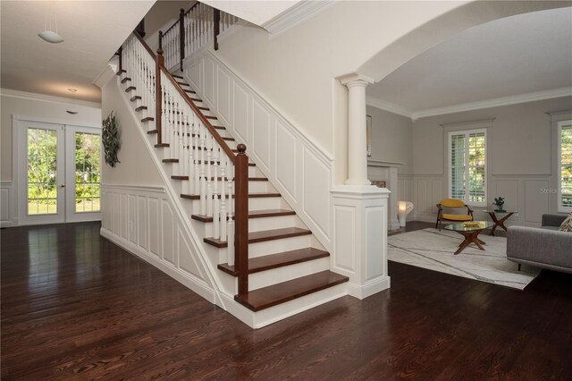 stairs with a decorative wall, wood finished floors, ornamental molding, arched walkways, and french doors