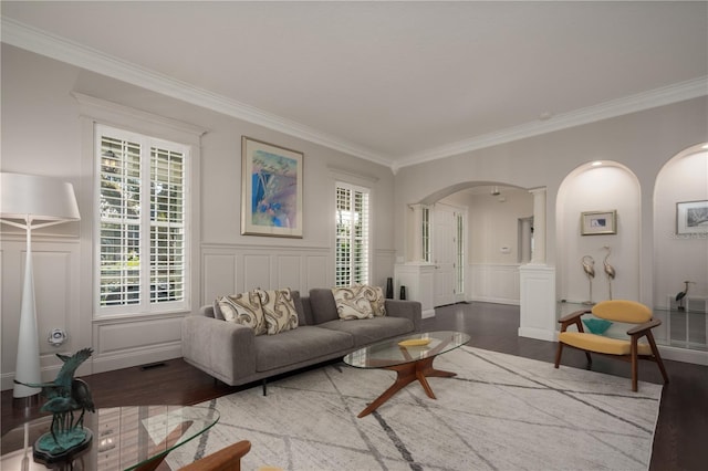 living area with arched walkways, wood finished floors, a decorative wall, ornamental molding, and decorative columns