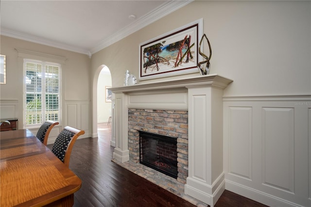office area with a decorative wall, a fireplace with flush hearth, arched walkways, ornamental molding, and dark wood finished floors