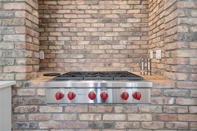 kitchen featuring stainless steel gas stovetop and brick wall