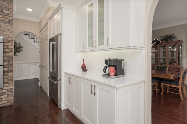 kitchen with freestanding refrigerator, ornamental molding, dark wood finished floors, glass insert cabinets, and white cabinetry