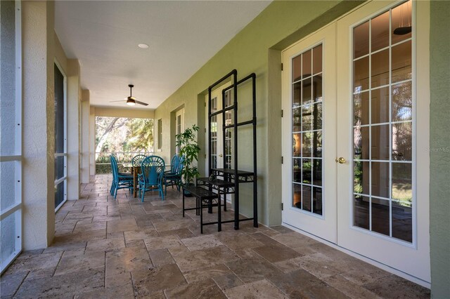 sunroom / solarium featuring french doors, stone tile floors, and outdoor dining space