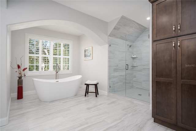 full bathroom featuring baseboards, a stall shower, and a freestanding bath