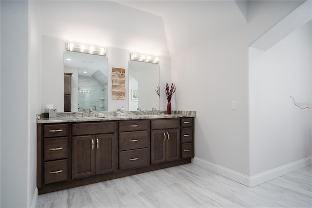 bathroom with a shower stall, baseboards, and double vanity