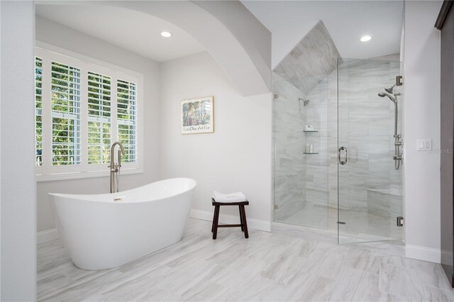 bathroom with a shower stall, baseboards, a soaking tub, and recessed lighting