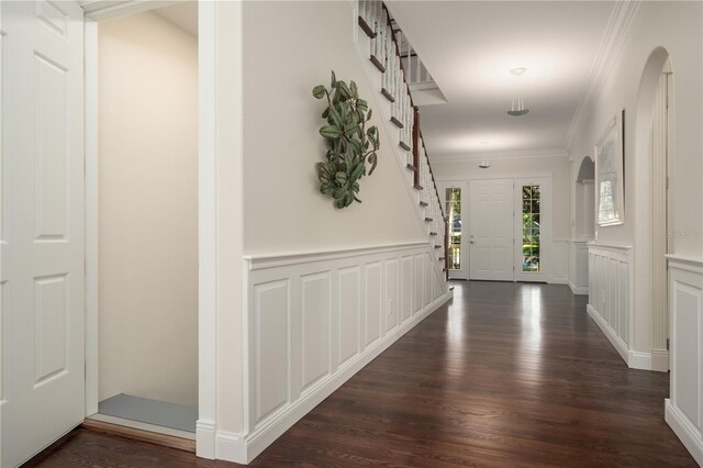 corridor with ornamental molding, dark wood-style flooring, a decorative wall, and a wainscoted wall