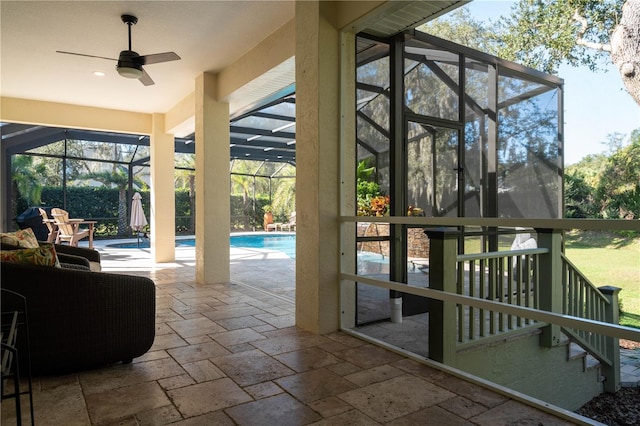 doorway to outside with stone tile floors, a sunroom, ceiling fan, and healthy amount of natural light