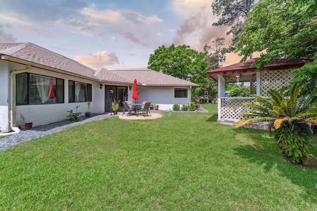25 Westlawn Pl, Palm Coast, FL 32164 - back of property at dusk featuring a yard, a patio, roof with shingles, and stucco siding