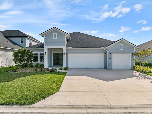 traditional home with a garage, concrete driveway, a front lawn, and roof with shingles