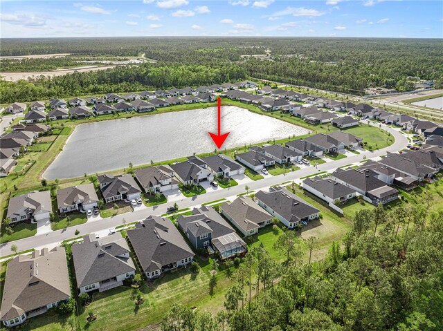 view of property location featuring nearby suburban area, a forest, and a large body of water