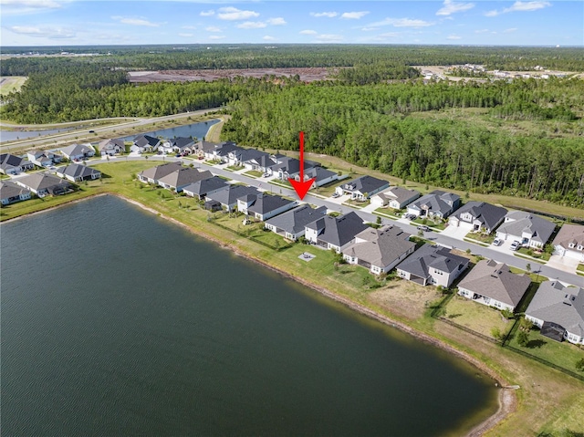 view of property location with nearby suburban area, a heavily wooded area, and a nearby body of water