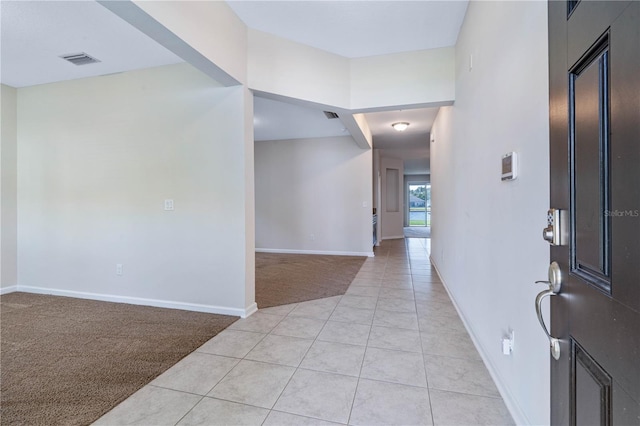 foyer entrance featuring light carpet, light tile patterned floors, and baseboards