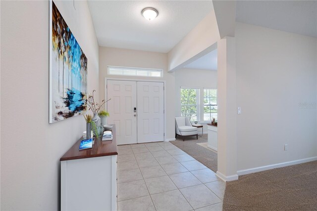 entryway featuring light carpet, light tile patterned flooring, and baseboards