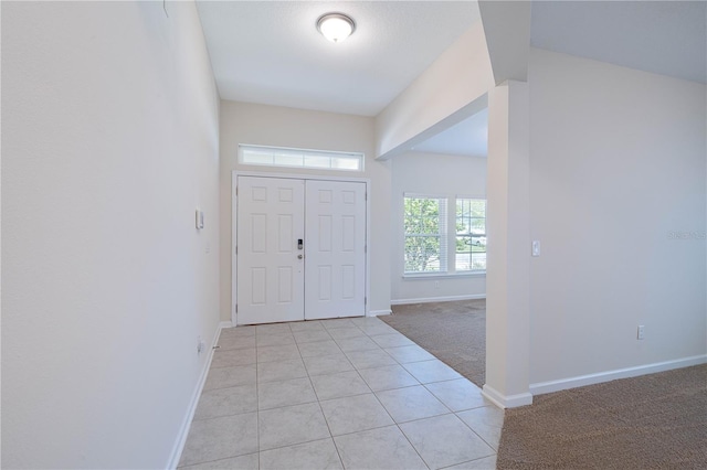 entryway featuring light carpet, baseboards, and light tile patterned floors