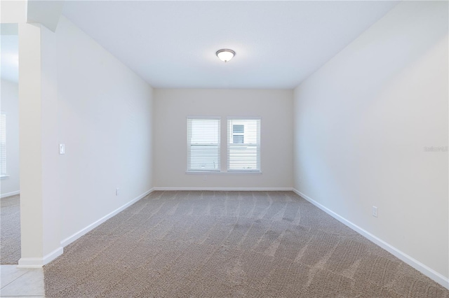 unfurnished room featuring light carpet and baseboards