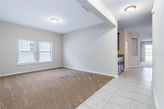 empty room featuring light carpet, baseboards, and light tile patterned floors