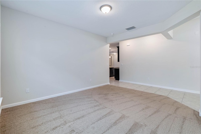 carpeted empty room featuring baseboards and tile patterned flooring