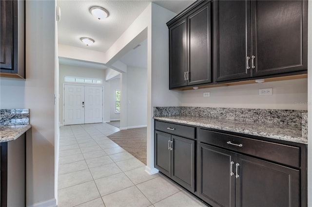 kitchen with light tile patterned floors, baseboards, and light stone counters