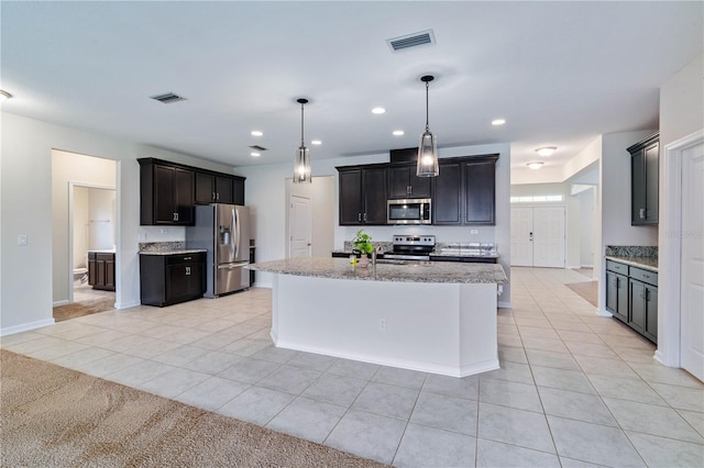 kitchen featuring appliances with stainless steel finishes, light tile patterned floors, light stone countertops, baseboards, and a kitchen island with sink