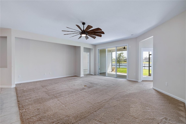 spare room with ceiling fan, baseboards, and light carpet