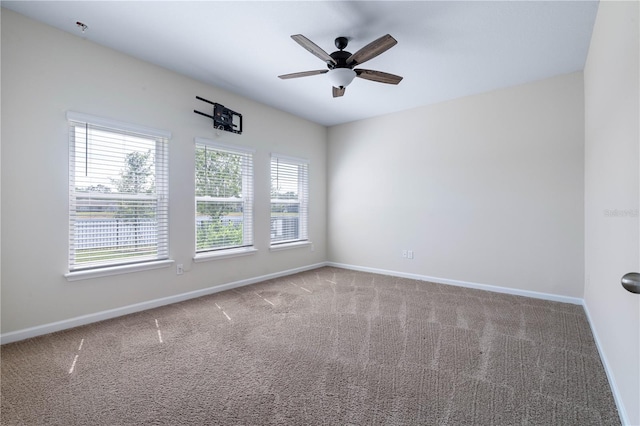 carpeted empty room with baseboards, ceiling fan, and a pendent fire sprinkler