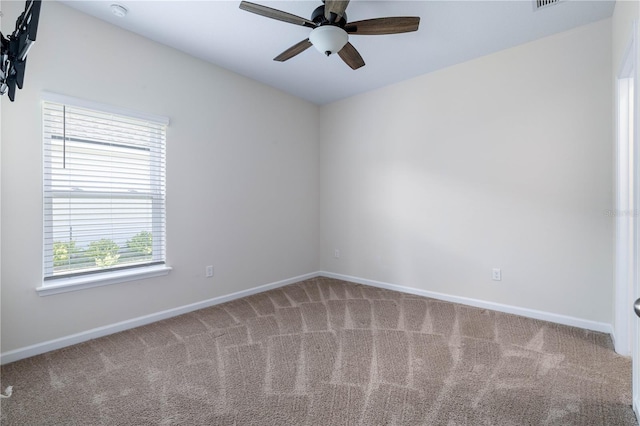 carpeted empty room featuring a ceiling fan and baseboards
