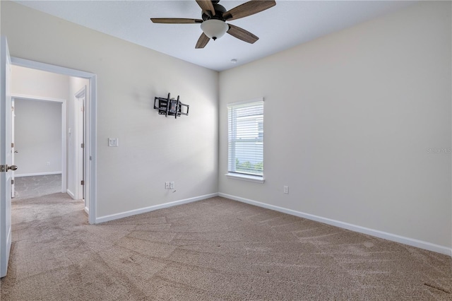 carpeted spare room featuring baseboards and ceiling fan
