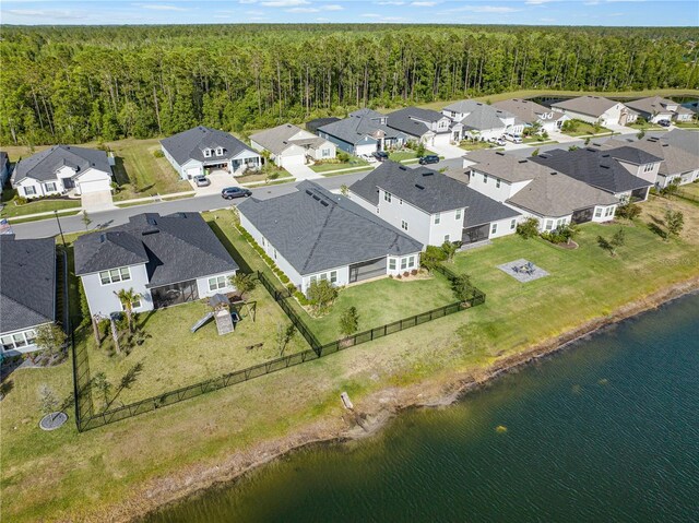 aerial perspective of suburban area with a forest and a large body of water