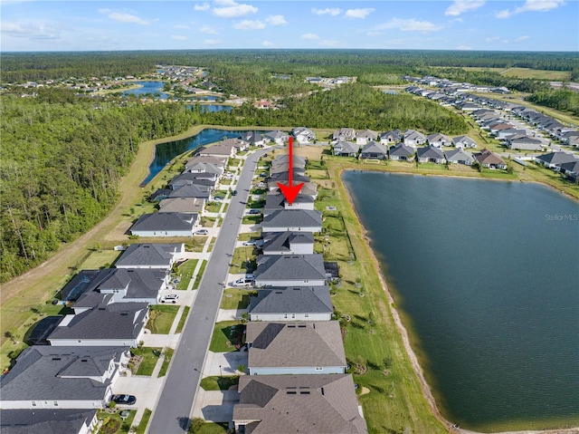 view of property location featuring nearby suburban area, a nearby body of water, and a forest