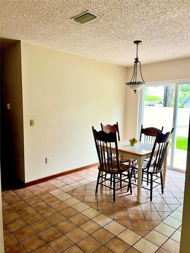 dining room with light tile patterned floors, visible vents, and a textured ceiling