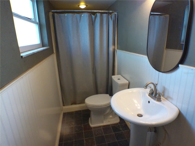 bathroom featuring toilet, a shower with curtain, a wainscoted wall, and tile patterned floors
