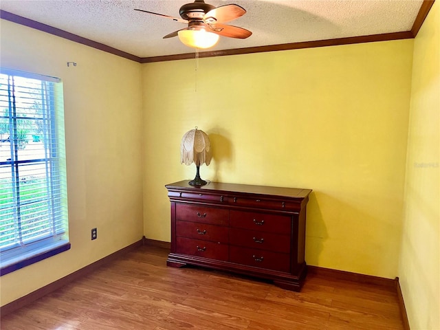 bedroom featuring crown molding, a textured ceiling, baseboards, and wood finished floors