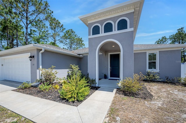 view of front of property with a garage, stucco siding, a shingled roof, and driveway