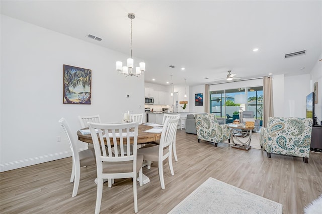 dining space with ceiling fan with notable chandelier, baseboards, visible vents, and light wood-style floors