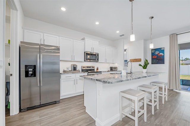 kitchen with light stone counters, a sink, white cabinetry, light wood-style floors, and stainless steel appliances