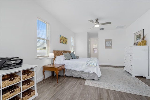 bedroom with baseboards, visible vents, a ceiling fan, and wood finished floors