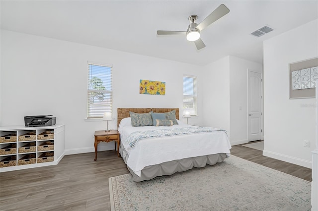 bedroom with ceiling fan, baseboards, visible vents, and wood finished floors