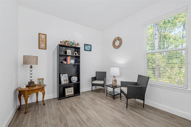 living area featuring plenty of natural light, light wood-style flooring, and baseboards