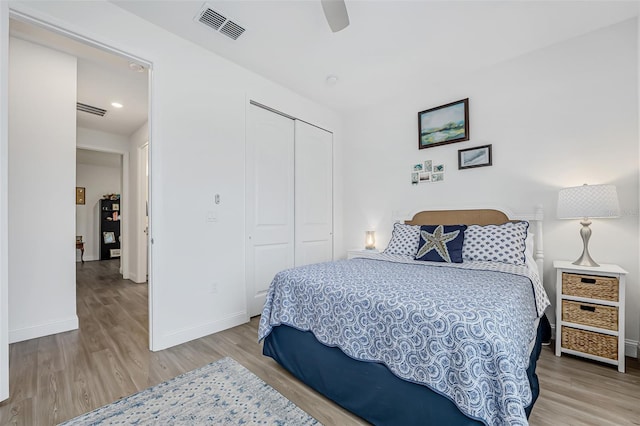 bedroom with baseboards, a closet, visible vents, and wood finished floors