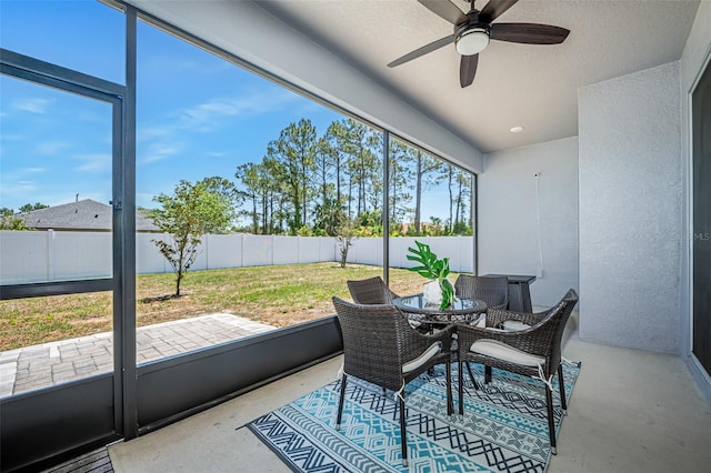 sunroom / solarium featuring outdoor dining area and a ceiling fan