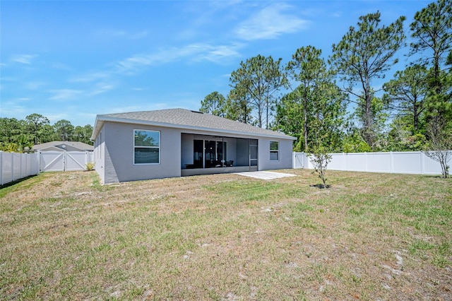 rear view of property featuring a gate, a ceiling fan, stucco siding, a fenced backyard, and a yard