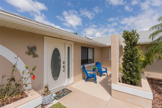 view of exterior entry featuring stucco siding and covered porch