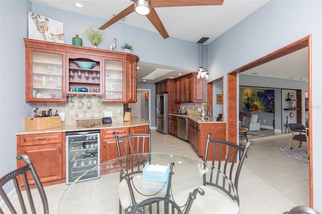 kitchen featuring decorative backsplash, wine cooler, light stone counters, a ceiling fan, and stainless steel appliances