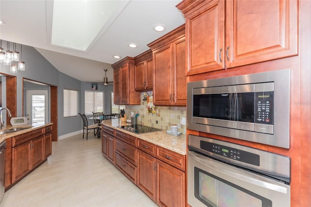 kitchen with decorative backsplash, baseboards, light stone counters, a sink, and stainless steel appliances