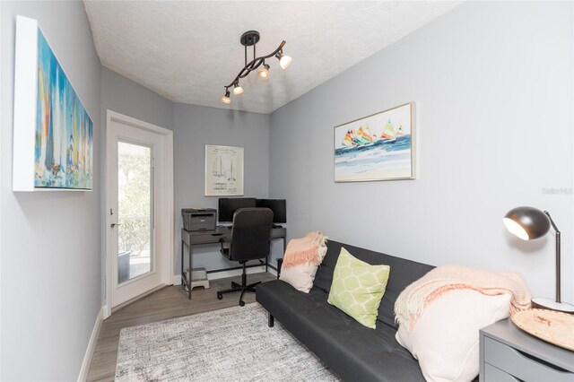 home office featuring a textured ceiling, baseboards, and wood finished floors