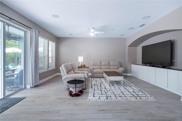 living room with baseboards, a ceiling fan, a textured ceiling, and wood finished floors