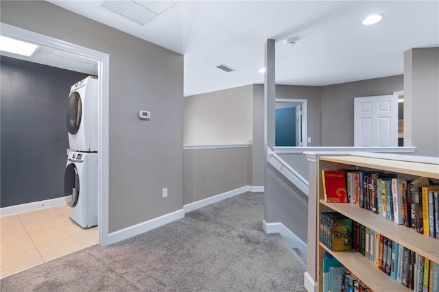 corridor featuring stacked washing maching and dryer, baseboards, carpet, and visible vents