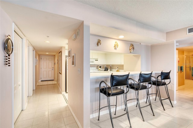 2937 S Atlantic Ave Unit 2001, Daytona Beach, FL 32118 - bar featuring light tile patterned floors, visible vents, baseboards, and white microwave