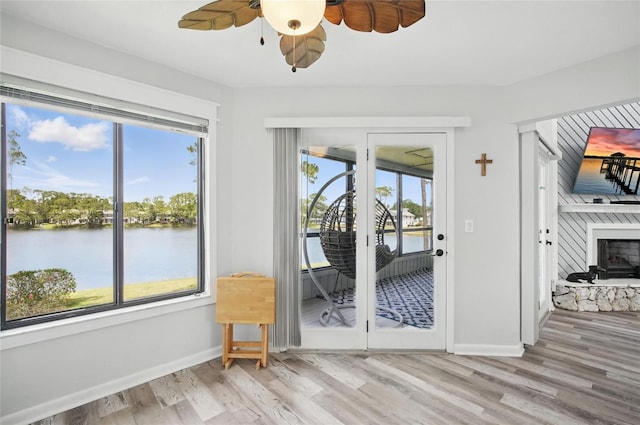 doorway to outside featuring baseboards, ceiling fan, a water view, and wood finished floors
