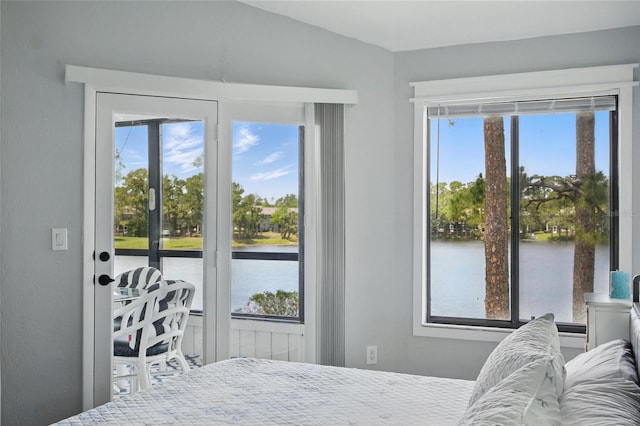 bedroom featuring a water view and multiple windows